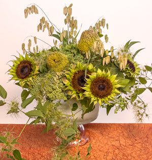 A lush textural design in shades of green full of clematis vine, de-petaled sunflowers, banksia, sedum, and rattlesnake grass.