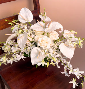 A lovely hand-tie bouquet combining tropical anthuriums, dendrobium orchids, and ti leaves with temperate vendela roses.