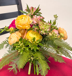 A vibrant wedding bouquet comprised of Symbol and Darcey garden roses, Fashonista alstromeria, ranunculus, flowering pittosporum, Italian ruscus and umbrella fern.