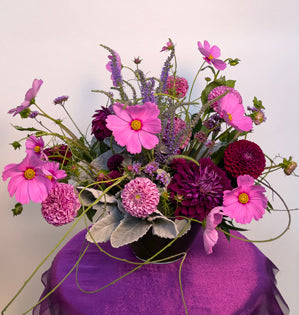 A lovely compote design made with, dusty miller, ruscus, wisteria vine, chrysanthemums, dahlias, veronica, statice, and cosmos.