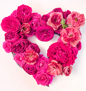 A lush heart shaped arrangement consisting of a variety of roses, and butterfly ranunculus, all in tints, tones, and shades of the Pantone Color of the Year - Viva Magenta.