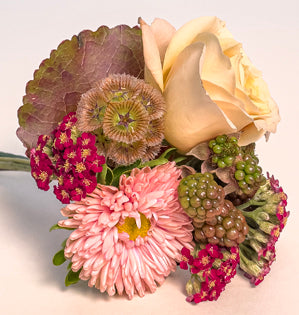 A pin-on wedding corsage made with ornamental blackberries, spray roses, cottage yarrow, scabiosa pod, matsumato aster and a galax leaf.