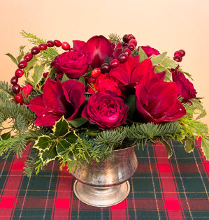 A silver compote full of cedar, noble fir, variegated holly, carnations, Tess garden roses, and amaryllis, topped with a cranberry garland.