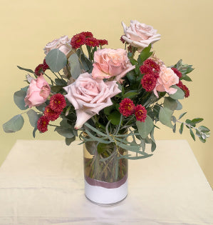 Quicksand and Sahara Sensation garden roses in a simple vase are paired with red spray mums, silver dollar and feather Eucalyptus, Green Mountain pittosporum and Israeli ruscus.