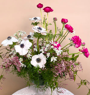 A lovely glass compote full of sprengeri, aspidistra, pieris, jasmine vine, ranunculus, orlaya, and anemone.