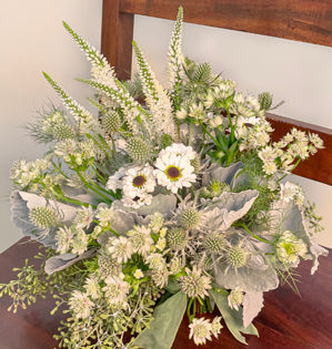 A stunning silver, white and green bouquet comprised of veronica, spray mums, astrantia, nigella, eryngium, seeded eucalyptus, on a base of dusty miller.