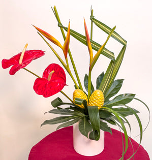 A dynamic hand-tied bouquet comprised of parakeet heliconia, anthurium, beehive ginger, hala, fatsia, aspidistra, and lily grass.
