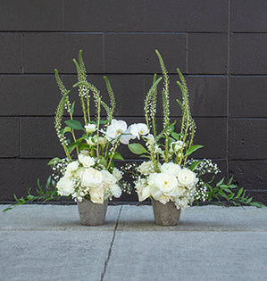 A pair of vertical floral designs mix white garden roses, hydrangea, veronica, and baby's breath, then a phalaenopsis orchid is used to tie the duo together.