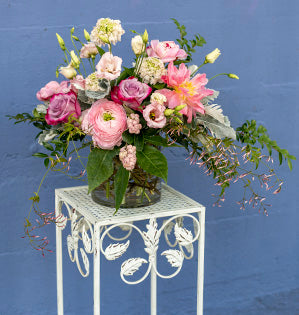 A casual foam-free design in pink hues features peonies, blueberry roses, scabiosa, ranunculus, lisianthus, snowberry, jasmine, huckleberry, fatsia and dusty miller.