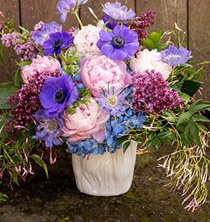 A fabulous foam-free bouquet in pink and periwinkle is full of summer blooms like peonies, lilac, hydrangea, jasmine vine, and anemones.