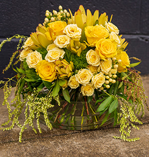 A vibrant yellow hand-tied and eco-conscious design has a cheerful mix of Regatta roses, Lemon Ice spray roses, hypericum, green trick dianthus, leucadendron, and pieris.