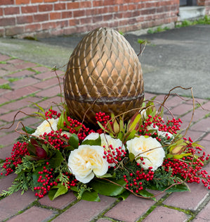 A floral ring design featuring garden roses and a large copper egg in the center.