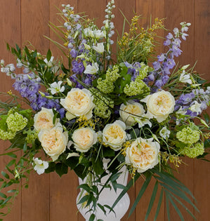 Church altar arrangement featuring garden roses, delphinium, viburnum, and lush seasonal greens