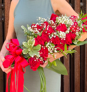 A classic presentation-style arm bouquet featuring radiant red roses, delicate baby's breath, and lush foliage.