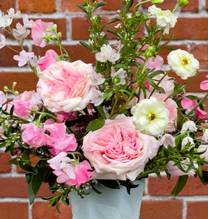 Blush roses, airy blossoms, and dancing stems in a white vase.