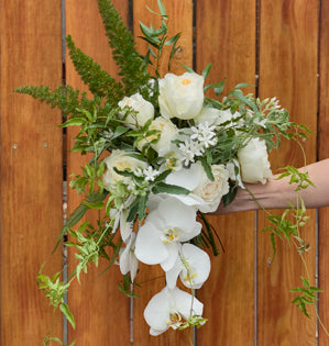 Wedding Bouquet with White roses, orchids, and textured foliage.