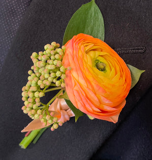 A simple orange ranunculus boutonnière.