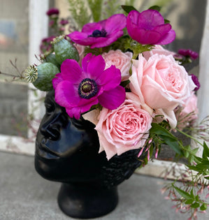 Black vase with pink and purple flowers on a light background