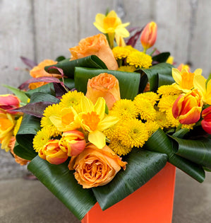 Bouquet of flowers with yellow and orange flowers in an orange container on a gray background