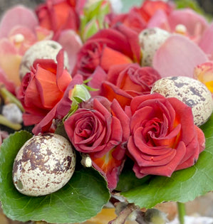 red roses and small eggs together in n arrangement.