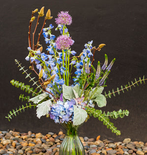Bouquet of wildflowers in a clear vase on a dark background