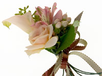 A nosegay is a small cluster of flowers, designed as a tiny bouquet and this lovely corsage mixes miniature callas, small roses, alstroemeria florets, hypericum, seeded eucalyptus, and a galax leaf.