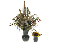 A Halloween floral design with flowers and foliage in muted fall colors is enhanced with spider webs made from glue sticks, a glue gun, and styrofoam.