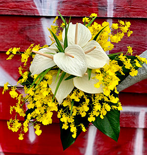 A hand-tied bouquet features elegant white anthurium, bamboo foliage, oncidium orchids (also know as “dancing Ladies”) and a collar of anthurium foliage.