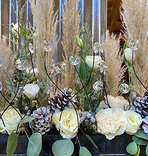 A parallel design in the vegetative style features three kinds of garden roses: Leonora, Eugenie, and Princess Miyuki mixed with lisianthus, berzillia, evergreens, pampas grass, eucalyptus, and pine cones.