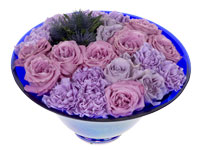 This lovely pave' floral design mixes blooms with lavender and purple hues in a round blue ceramic bowl. This beautiful arrangement includes Cool Water roses, carnations, eryngium, and Ocean Song spray roses.
