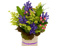 A lovely bouquet of purple hyacinths, solid aster, hypericum, and Gaelic sleeves in a country-style vase covered in burlap.