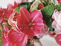 A closeup of a bouquet of lilies, peonies, and carnations in shades of pink.