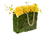 Three bright yellow roses and small branches of yellow oncidium orchids burst from the top of a small handbag covered in galax leaves with a rhinestone strap.