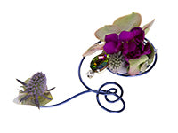 A contemporary boutonniere made from a spiral of aluminum wire decorated with little bits of hydrangea, pieces of a succulent, eryngium, a single stock florette, and a peacock-hued jewel.