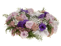 A table wreath with shiny silver balls, icy white excelsior grass, sparkly white ribbon, pink heather, evergreen bits, soft purple roses, rice flower, and deep purple lisianthus. 