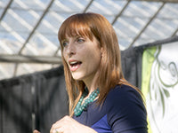 Susan McCleary speaking. Susan is wearing a turquoise necklace and a blue and black dress.