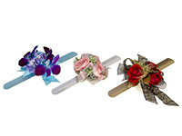 Three wrist corsages: one blue with blue ribbon, purple blooms, and diamante pins, one silver with pink ribbon and roses, succulents, and dusty miller all dusted with glitter, and one gold with black ribbon, red roses, gilded leaves, and dried grasses.