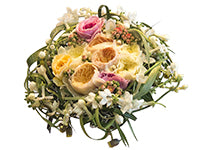 A bouquet with vines and long leaves woven into a framing nest, featuring peonies and roses of pink, yellow, and soft orange and other small white blooms wrapped into the nest.