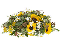 A low table centerpiece of summer sunflowers, garden wildflowers like yarrow and feverfew, blackberries, kale, poppy pods, various foliages, and crawling barked wire.