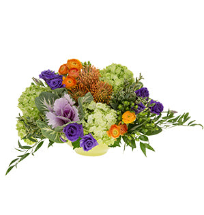 A floral centerpiece in a triadic color harmony using green hydrangea, ranunculus, pin cushion protea, lisianthus and kale.