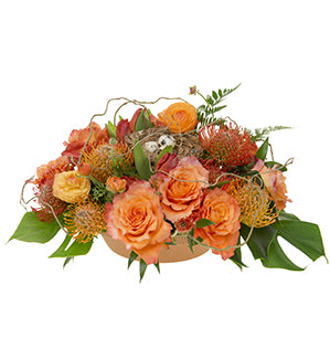 A dramatic centerpiece combines spring tulips and ranunculus, "Free Spirit" garden roses and exotic pincushion protea, ruscus, monsterra and aspidistra leaves, leather fern, finished with a bird’s nest filled with quail eggs.