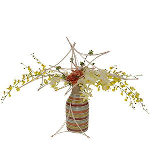 A floral arrangement in a multicolor striped base uses an armature of triangles fashioned from rattan midollino sticks and showcases draping oncidium orchids along with dahlias, cockscomb, and phalaenopsis orchids.