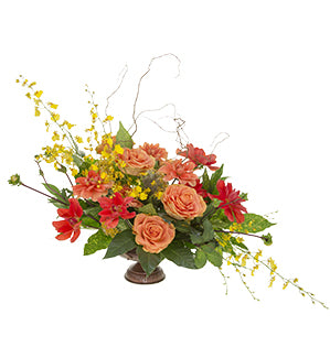 An eclectic design combining fabulous dahlias and garden roses plus a surprising addition of oncidium orchids, with foliages of aucuba, camellia, and fatsia, arranged in Western Line Style inside a bronze compote vessel and accessorized with curly willow.