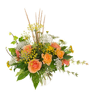 A full, lush bouquet of tangerine and coral garden roses, bright yellow tansy, Oregonia, and Aucuba, gets a wild, foraged look from the additions of Queen Anne's lace, fennel, camellia leaves, semi-dried grasses, maple, and ivy and rests in a bubble bowl.