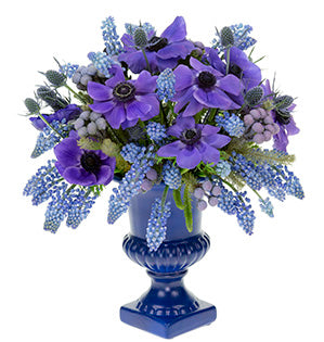 A spring bouquet in a color palette of blues includes muscari, anemones, eryngium, and Brunia dyed a blue-lavender, sits in a footed urn of matching blue.