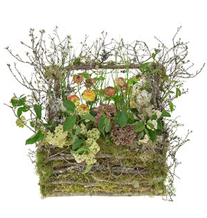 A woodland arrangement of tall viburnum, variegated ranunculus, antique hydrangea, and natural grasses resembling weeds nestled inside a box fashioned from moss and lichen-covered twigs and branches.