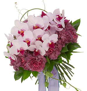 A classic round hand-tied bouquet of carnations at the base, ruscus leaves, and loads of Phalaenopsis orchids draws a dynamic line with the addition of passion vine winding around and through.