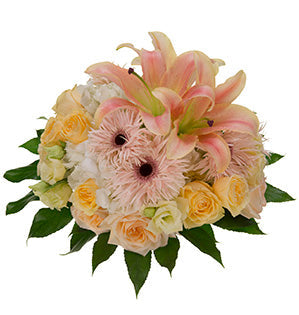 A luscious, feminine wedding bouquet mixes lilies, roses, lisianthus and Gerberas in coral and soft yellow color palette.