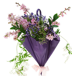 A purple umbrella is filled with spring blooms such as flowering plum, jasmine vine and agapanthus paired with spring flowering branches and Israeli ruscus.