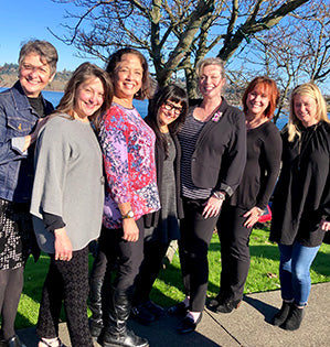 This lovely group photo of seven Floral Design Institute Instructors is taken outdoors under spring trees.